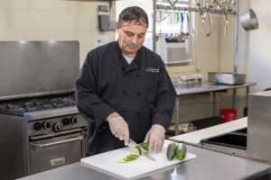 a chef preparing vegetables in the kitchen area at the West Village facility