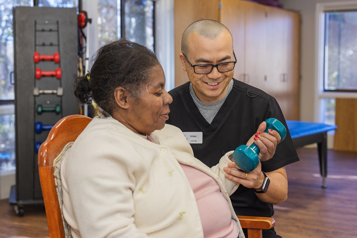 A rehab therapist with a resident in the rehab gym at the West Village facility