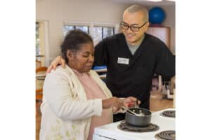 An occupational therapist with a resident in the rehab kitchen at the West Village facility