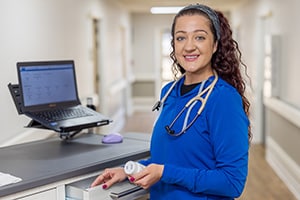 A nurse standing next to a nurse's cart in the hallway